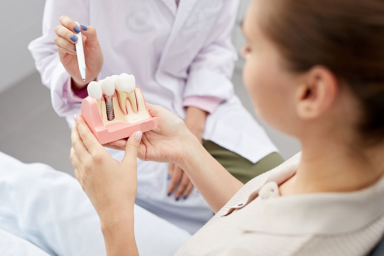 Patientin erhält eine Beratung zur Implantologie Essen anhand eines Zahnimplantat-Modells.