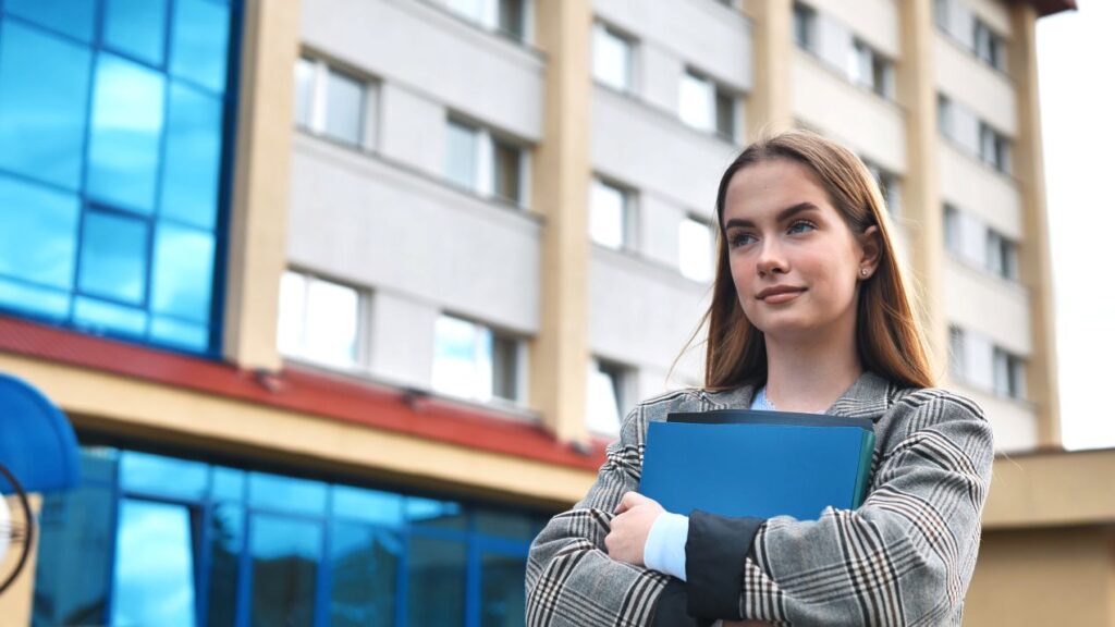 Junge Frau mit Unterlagen vor einem Gebäude – Symbol für die Vorbereitung auf den Verkehrskunde-Unterricht in Zürich.